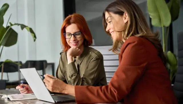 Dwie kobiety pracujące razem przy komputerze nad planowaniem projektu w biurze