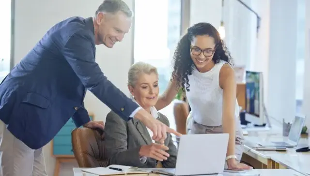 Trzy osoby przy laptopie podczas rozmowy biznesowej, współpracy i szkolenia w biurze