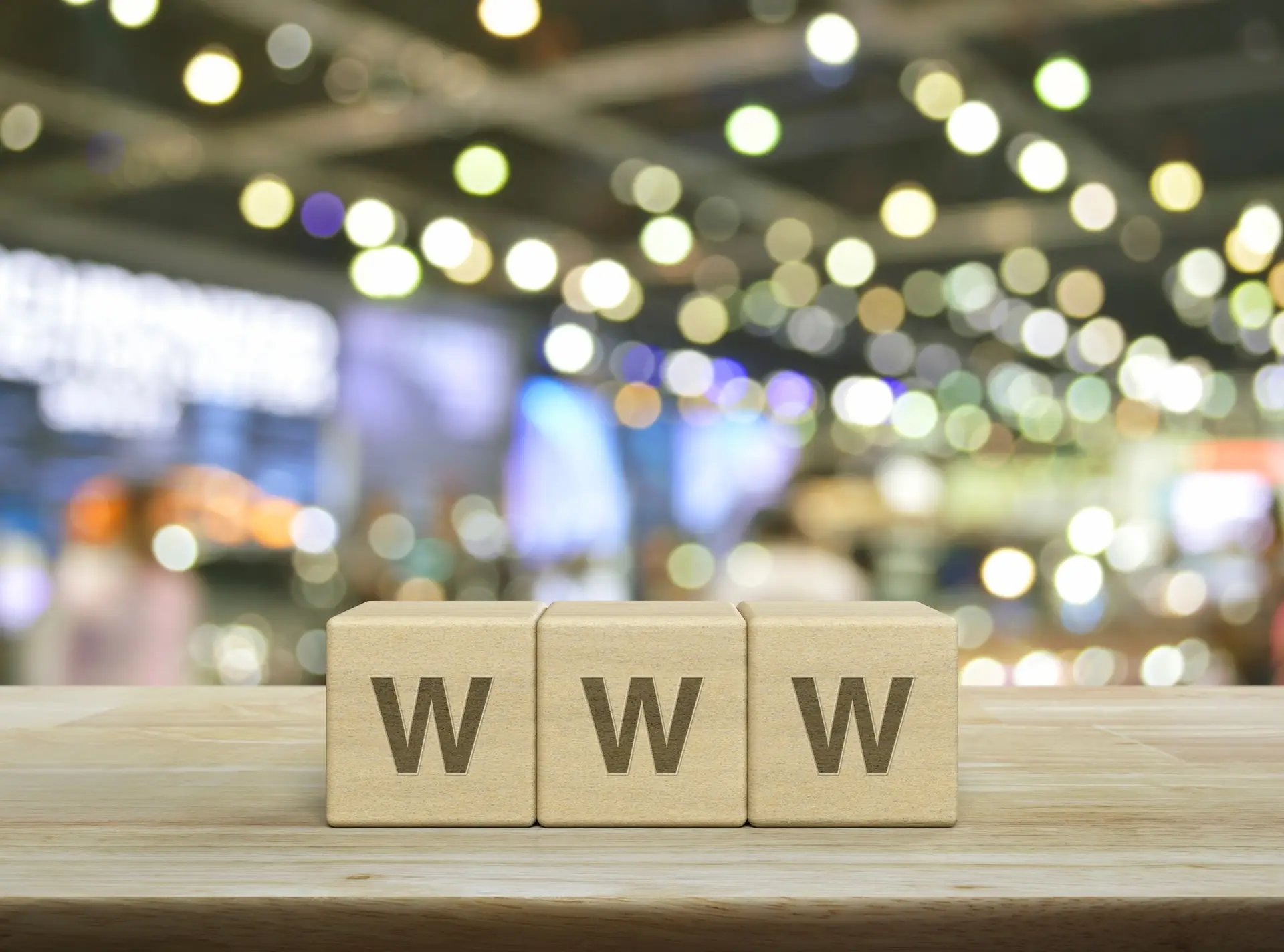 Litery WWW ułożone z drewnianych klocków na stole, symbolizujące internet i wyszukiwanie