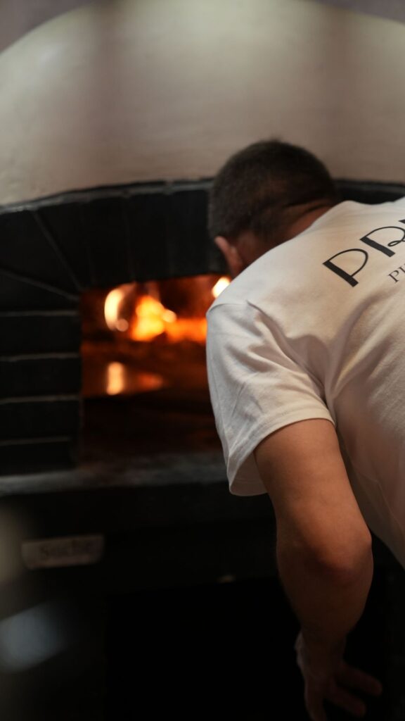Pizzaiolo przy piecu opalanym drewnem - kadr z sesji dla pizzerii