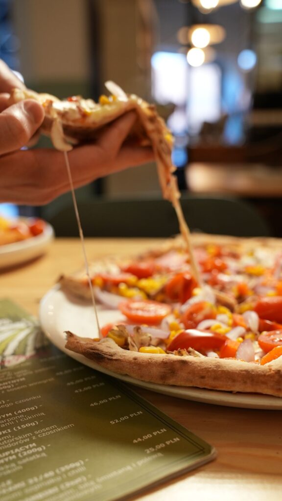 Pizza na stole z ciągnącym się serem - kadr do reklamy
